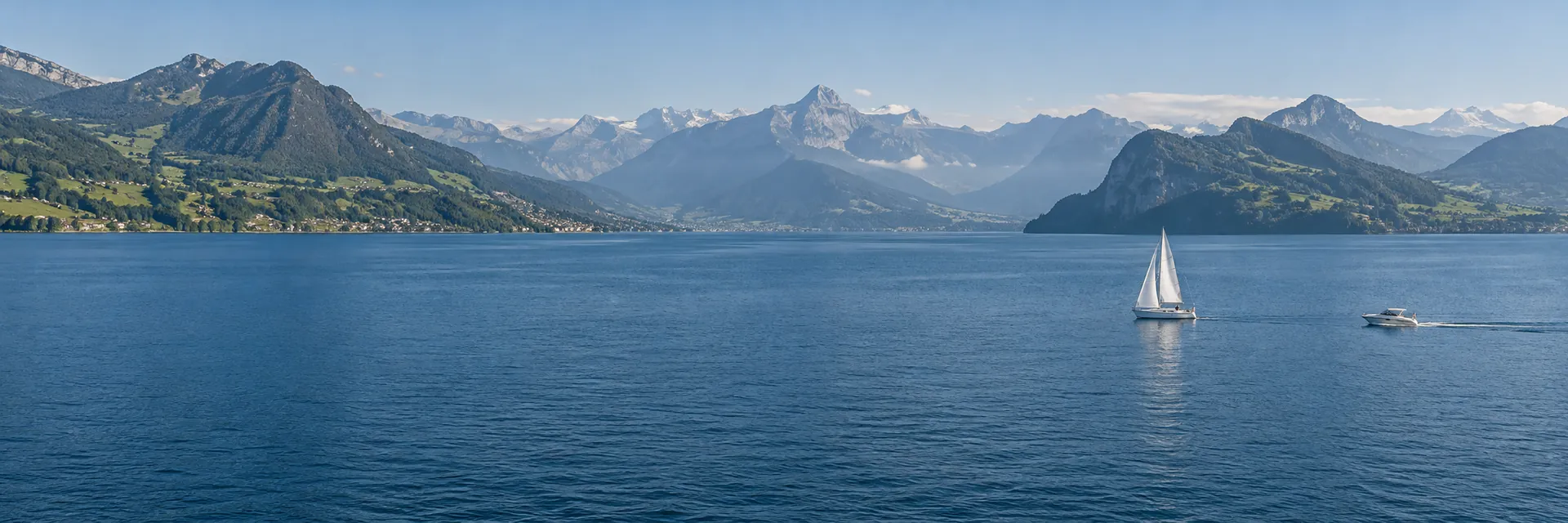 Segel- und Motorboot auf einem Schweizer See vor den Alpen